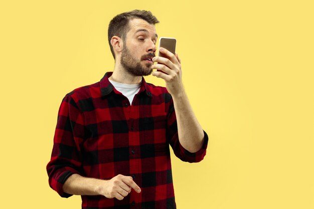 Ritratto alto vicino a mezzo busto di giovane uomo in camicia sullo spazio giallo. Le emozioni umane, il concetto di espressione facciale. Vista frontale. Colori alla moda. Spazio negativo