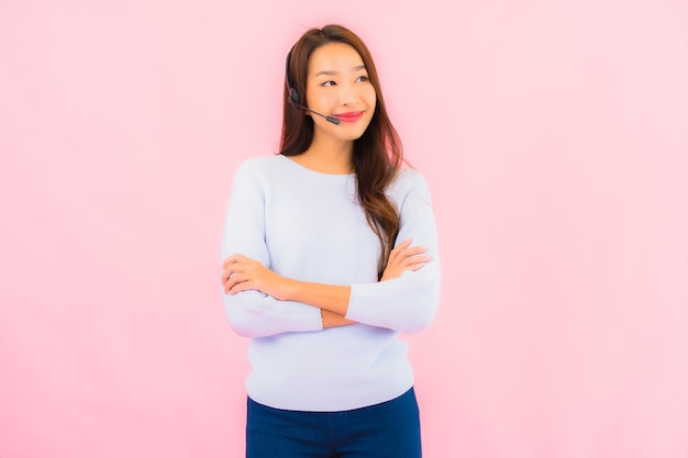 Ritratto bella giovane donna asiatica call center sulla parete isolata di colore rosa