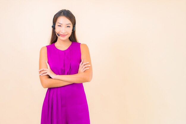 Ritratto bella giovane donna asiatica con auricolare per il cliente del call center su sfondo di colore
