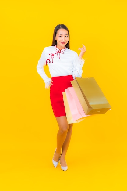 Ritratto bella giovane donna asiatica con borsa della spesa e carta di credito su yellow
