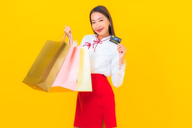 Ritratto bella giovane donna asiatica con borsa della spesa e carta di credito su yellow