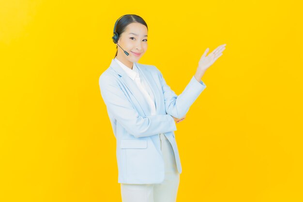 Ritratto bella giovane donna asiatica con call center customer care centro servizi su yellow