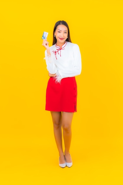 Ritratto bella giovane donna asiatica con carta di credito per lo shopping online su yellow