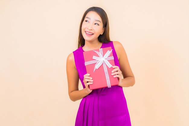 Ritratto bella giovane donna asiatica con confezione regalo rossa su sfondo di colore isolato