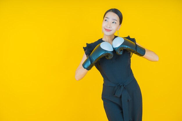 Ritratto bella giovane donna asiatica con guantoni da boxe su giallo