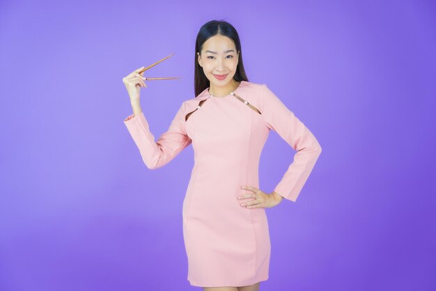 Ritratto bella giovane donna asiatica con le bacchette su sfondo colorato