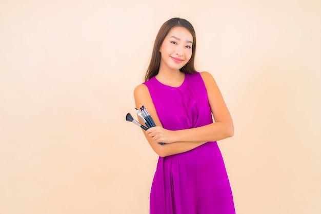 Ritratto bella giovane donna asiatica con trucco pennello su sfondo di colore isolato