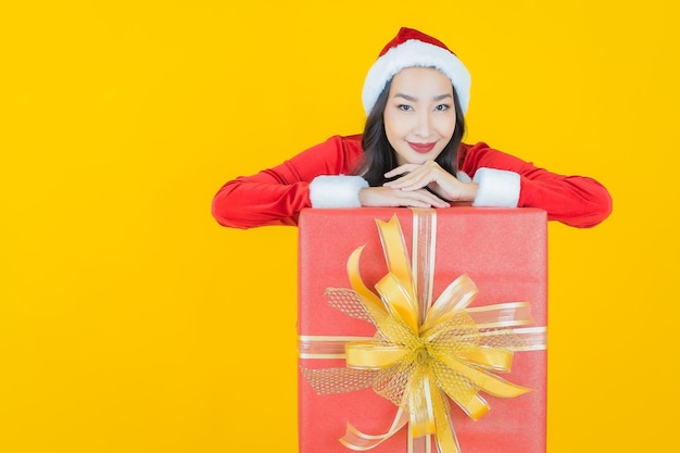 Ritratto bella giovane donna asiatica indossare il costume di Natale con confezione regalo rossa su giallo