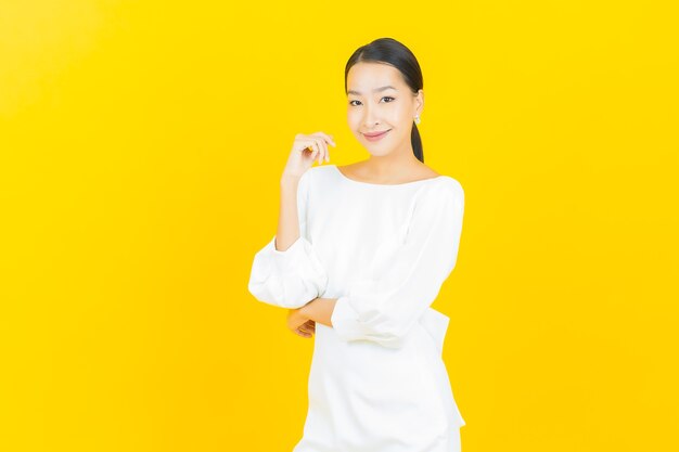 Ritratto bella giovane donna asiatica sorriso con azione su yellow