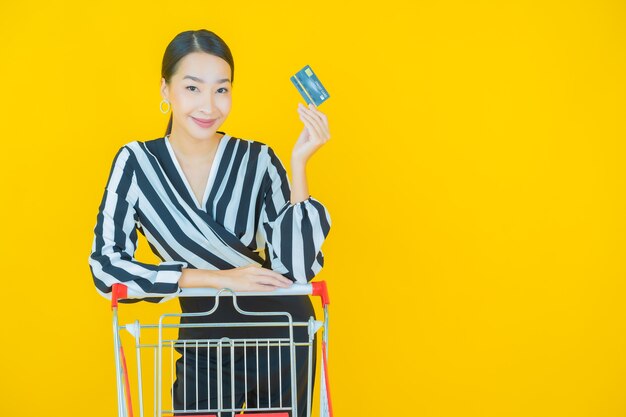 Ritratto bella giovane donna asiatica sorriso con cesto della spesa dal supermercato su yellow