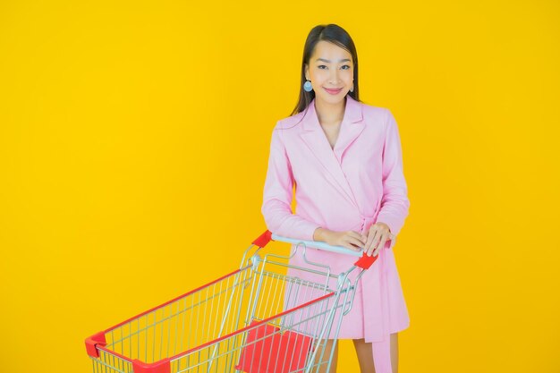 Ritratto bella giovane donna asiatica sorriso con cesto di generi alimentari dal supermercato su sfondo colorato