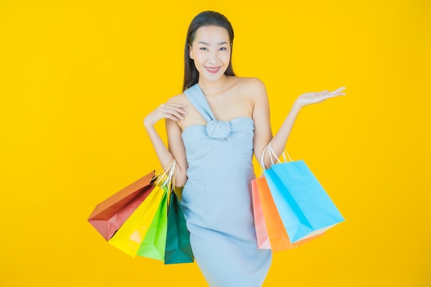 Ritratto bella giovane donna asiatica sorriso con la borsa della spesa su yellow