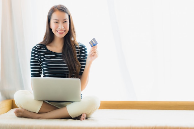 Ritratto bella giovane donna asiatica utilizzando computer notebook o laptop con carta di credito per lo shopping