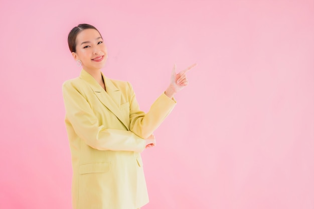 Ritratto bello giovane sorriso asiatico della donna di affari nell'azione sul colore rosa