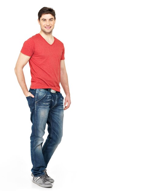 Ritratto completo dell'uomo bello felice sorridente in casuals rossi della maglietta isolati sulla parete bianca. Bello giovane ragazzo in posa
