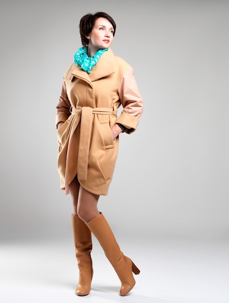 Ritratto completo di moda donna in cappotto beige autunno con sciarpa verde su sfondo grigio