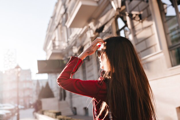 Ritratto dal retro della ragazza dai capelli lunghi che cammina per la città in una giornata di sole