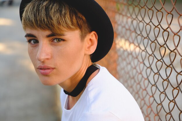Ritratto dei pantaloni a vita bassa femminili con trucco naturale e breve taglio di capelli che godono del tempo libero all'aperto