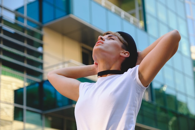 Ritratto dei pantaloni a vita bassa femminili con trucco naturale e breve taglio di capelli che godono del tempo libero all'aperto