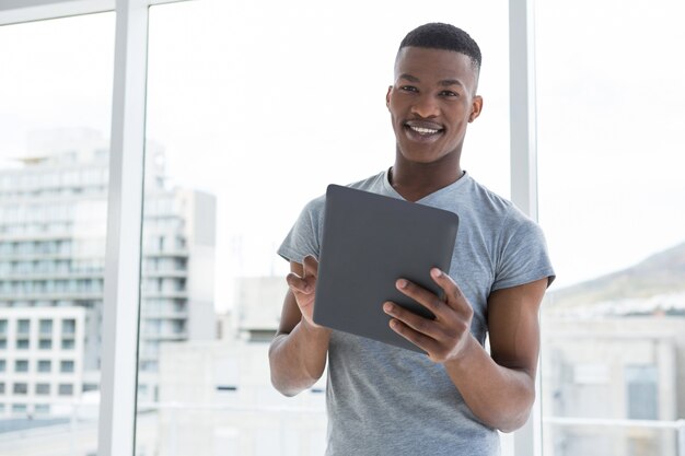 Ritratto del ballerino sorridente che per mezzo della compressa digitale