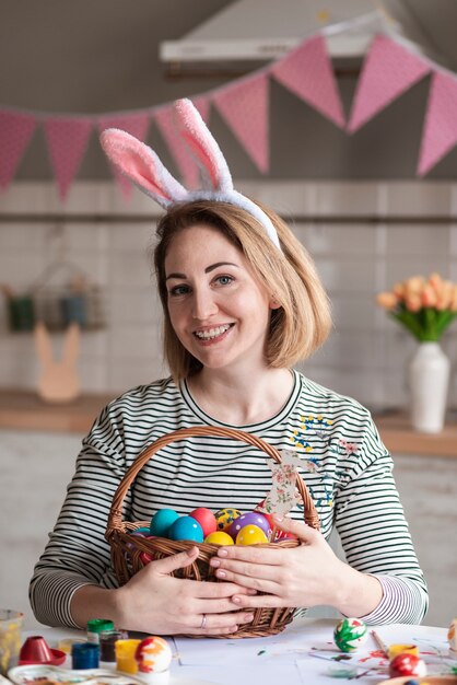 Ritratto del canestro adorabile della tenuta della donna con le uova di Pasqua