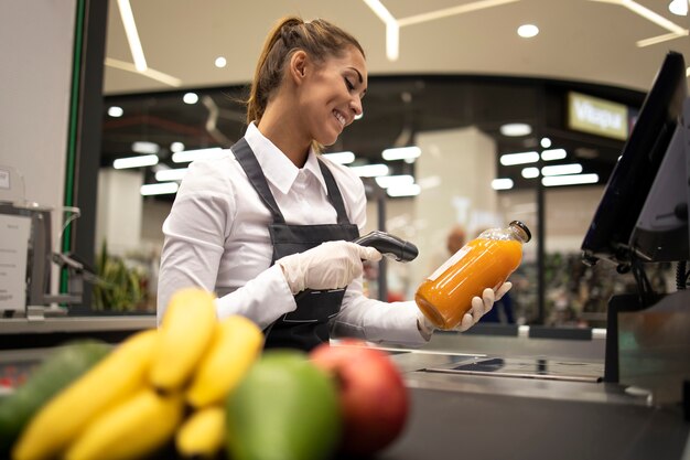 Ritratto del cassiere femminile nel codice a barre di scansione del supermercato dei prodotti in vendita