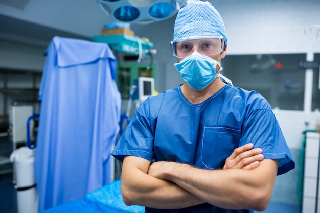 Ritratto del chirurgo in piedi con le braccia incrociate in sala operatoria