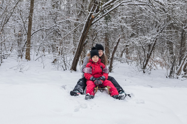Ritratto del fratello e della sorella che si siedono sulla slitta di legno nel paesaggio nevoso