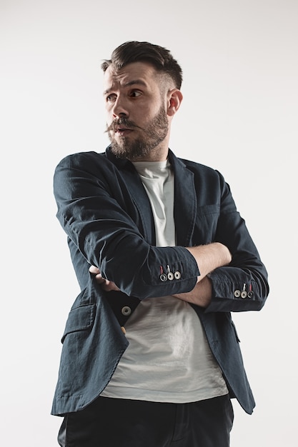 Ritratto del giovane bello alla moda che sta contro il bianco. Uomo che indossa una giacca