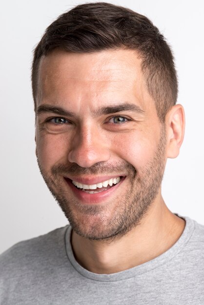 Ritratto del giovane sorridente in maglietta grigia che esamina macchina fotografica