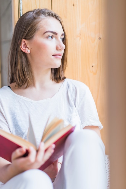 Ritratto del libro della holding della giovane donna che osserva via