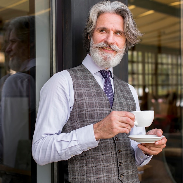 Ritratto del maschio elegante che gode del caffè