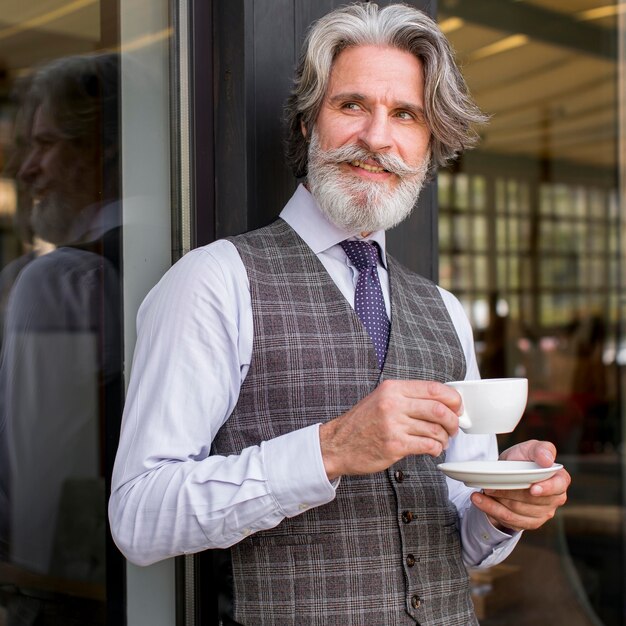 Ritratto del maschio elegante che gode del caffè