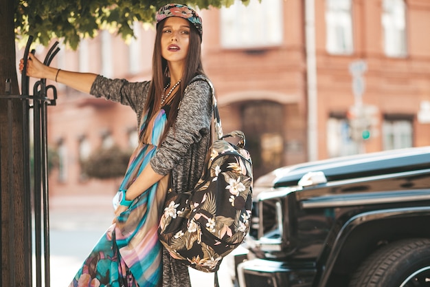 Ritratto del modello dell'adolescente del bello brunette di fascino in vestiti e borsa dei pantaloni a vita bassa di estate. Ragazza in posa in strada. Donna con cappello