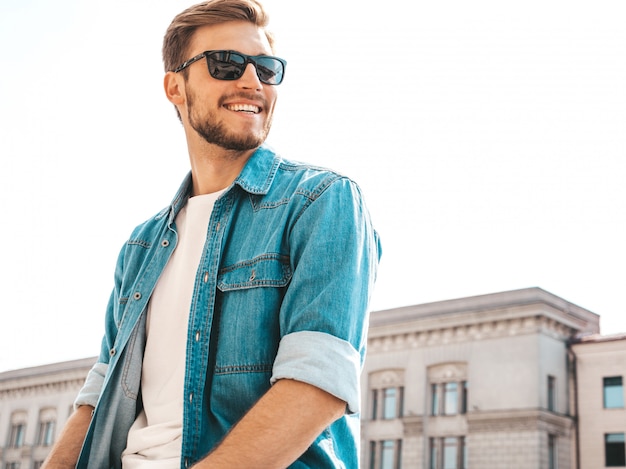 Ritratto del modello dell'uomo d'affari lumbersexual sorridente alla moda bello dei pantaloni a vita bassa. Uomo vestito con abiti giacca di jeans.