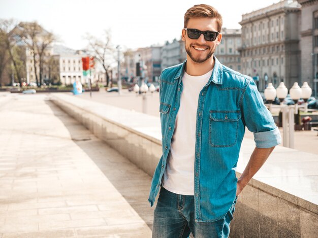 Ritratto del modello dell'uomo d'affari lumbersexual sorridente alla moda bello dei pantaloni a vita bassa. Uomo vestito con abiti giacca di jeans.