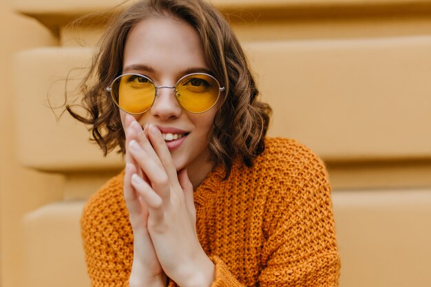 Ritratto del modello femminile grazioso interessato in maglione lavorato a maglia caldo