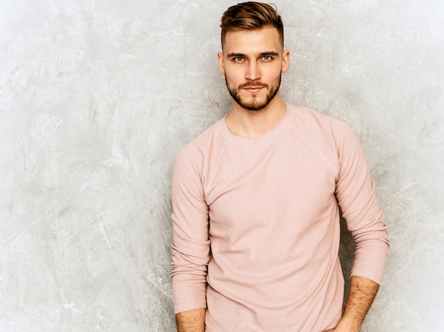 Ritratto del modello sicuro bello del giovane che indossa i vestiti casuali di rosa di estate. Posa alla moda dell'uomo di modo. luce del giorno