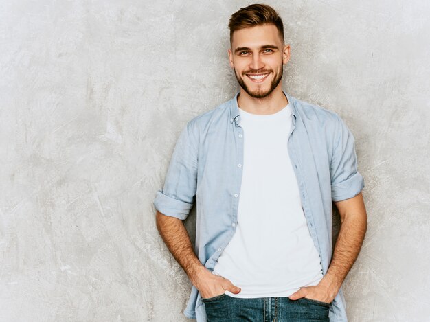 Ritratto del modello sorridente bello del giovane che indossa i vestiti casuali della camicia. Posa alla moda dell'uomo di modo