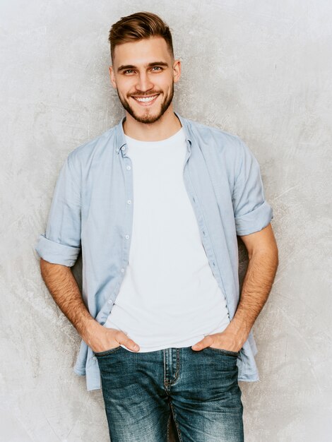 Ritratto del modello sorridente bello del giovane che indossa i vestiti casuali della camicia. Posa alla moda dell'uomo di modo