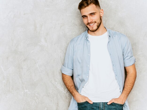 Ritratto del modello sorridente bello del giovane che indossa i vestiti casuali della camicia. Posa alla moda dell'uomo di modo