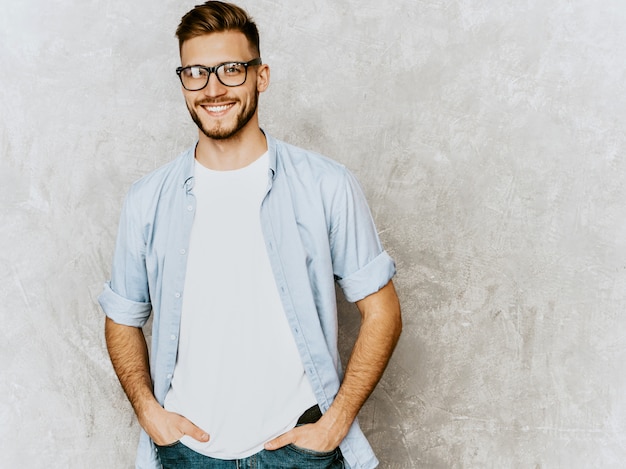 Ritratto del modello sorridente bello del giovane che indossa i vestiti casuali della camicia. Uomo alla moda di modo che posa in occhiali