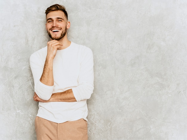 Ritratto del modello sorridente bello dell'uomo d'affari dei pantaloni a vita bassa che indossa i vestiti bianchi casuali di estate.