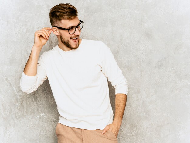 Ritratto del modello sorridente bello dell'uomo d'affari dei pantaloni a vita bassa che indossa i vestiti bianchi casuali di estate.