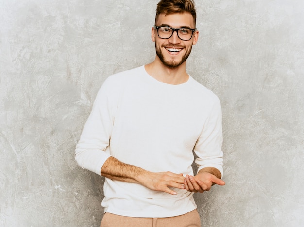 Ritratto del modello sorridente bello dell'uomo d'affari dei pantaloni a vita bassa che indossa i vestiti bianchi casuali di estate.