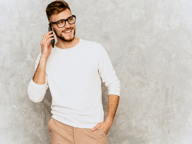 Ritratto del modello sorridente bello dell'uomo d'affari dei pantaloni a vita bassa che indossa i vestiti bianchi casuali di estate.