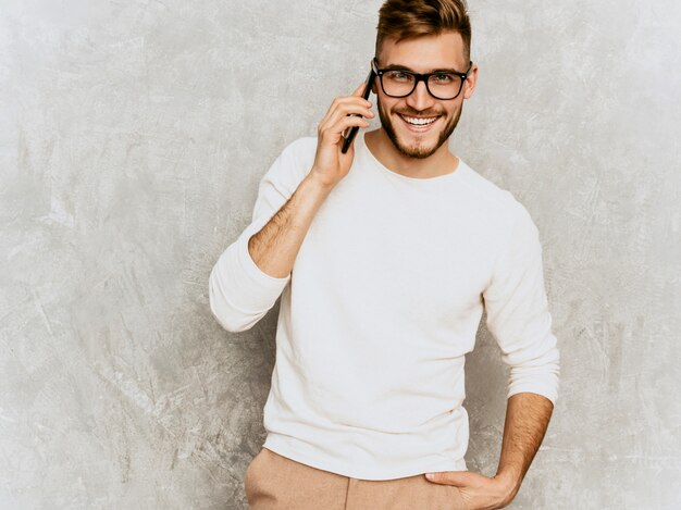 Ritratto del modello sorridente bello dell'uomo d'affari dei pantaloni a vita bassa che indossa i vestiti bianchi casuali di estate.