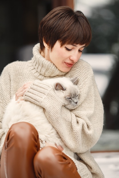 Ritratto del primo piano della donna in maglione bianco con il gatto bianco