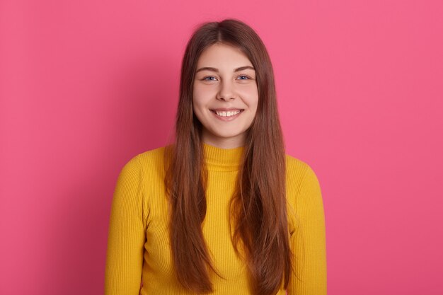 Ritratto del primo piano della femmina felice con il sorriso a trentadue denti, indossando camicia gialla casuale