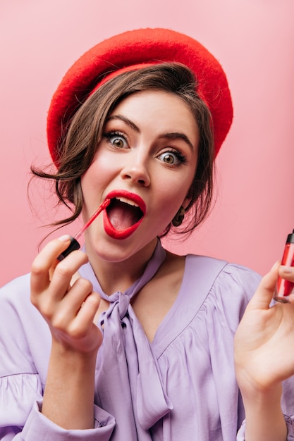 Ritratto del primo piano delle labbra allegre della pittura della ragazza dagli occhi verdi con rossetto rosso su fondo isolato.